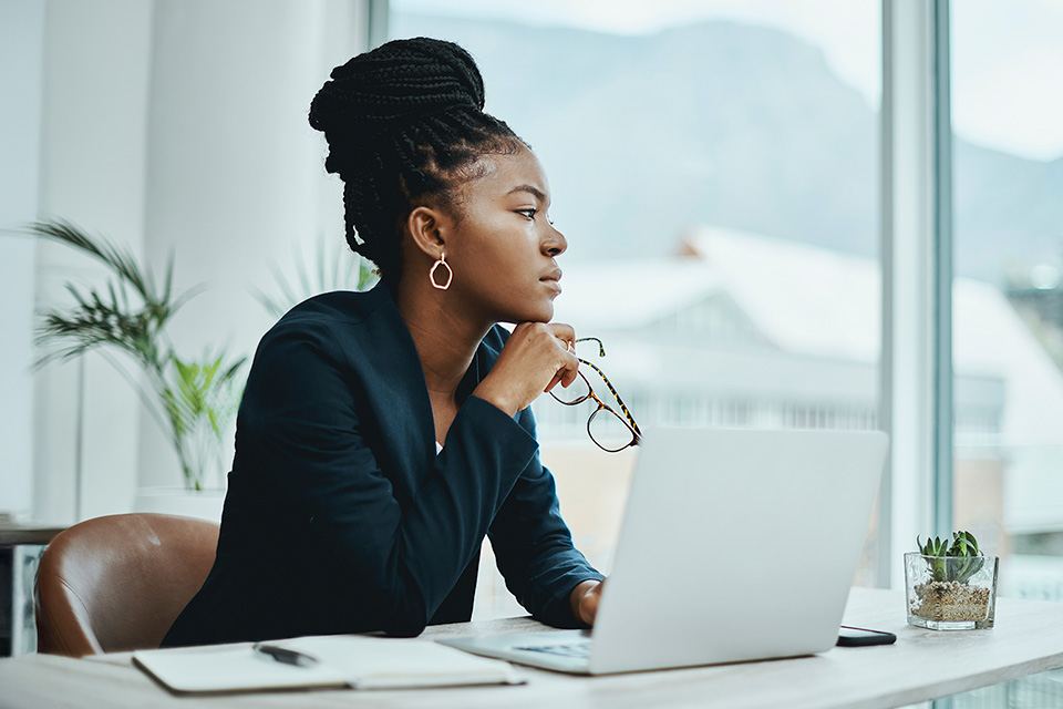 Woman sitting in front of a laptop looking thoughtful