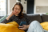 Woman sitting on her sofa while looking at her phone