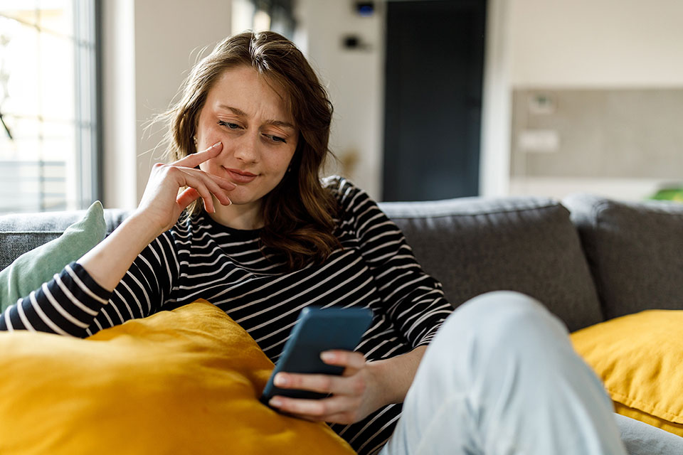 Woman sitting on her sofa while looking at her phone