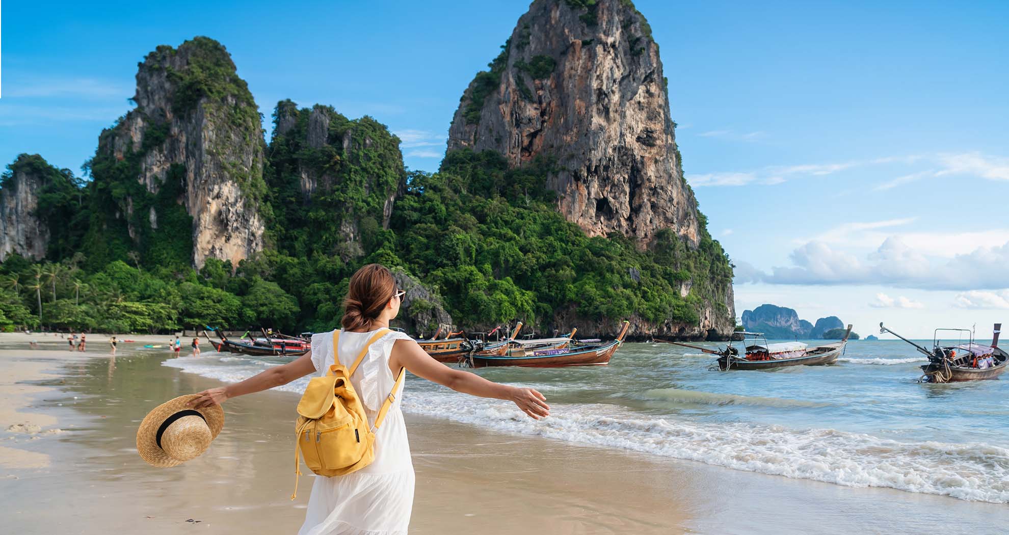 A woman on a beach in Thailand looking out at the sea.