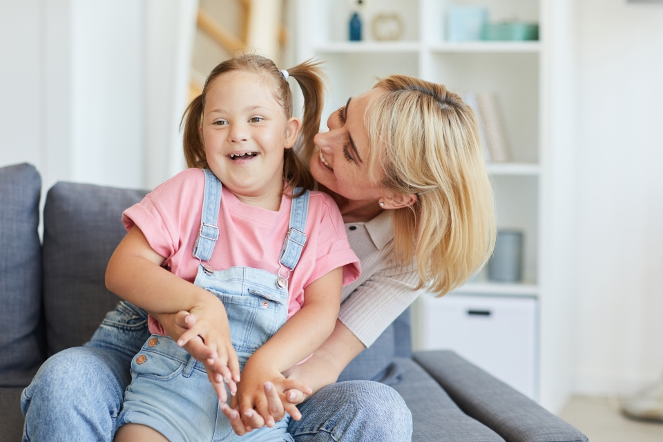 Mother embracing her daughter in the living room of their home.