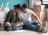A couple on the floor together in a room full of boxes choosing a paint colour for their walls.