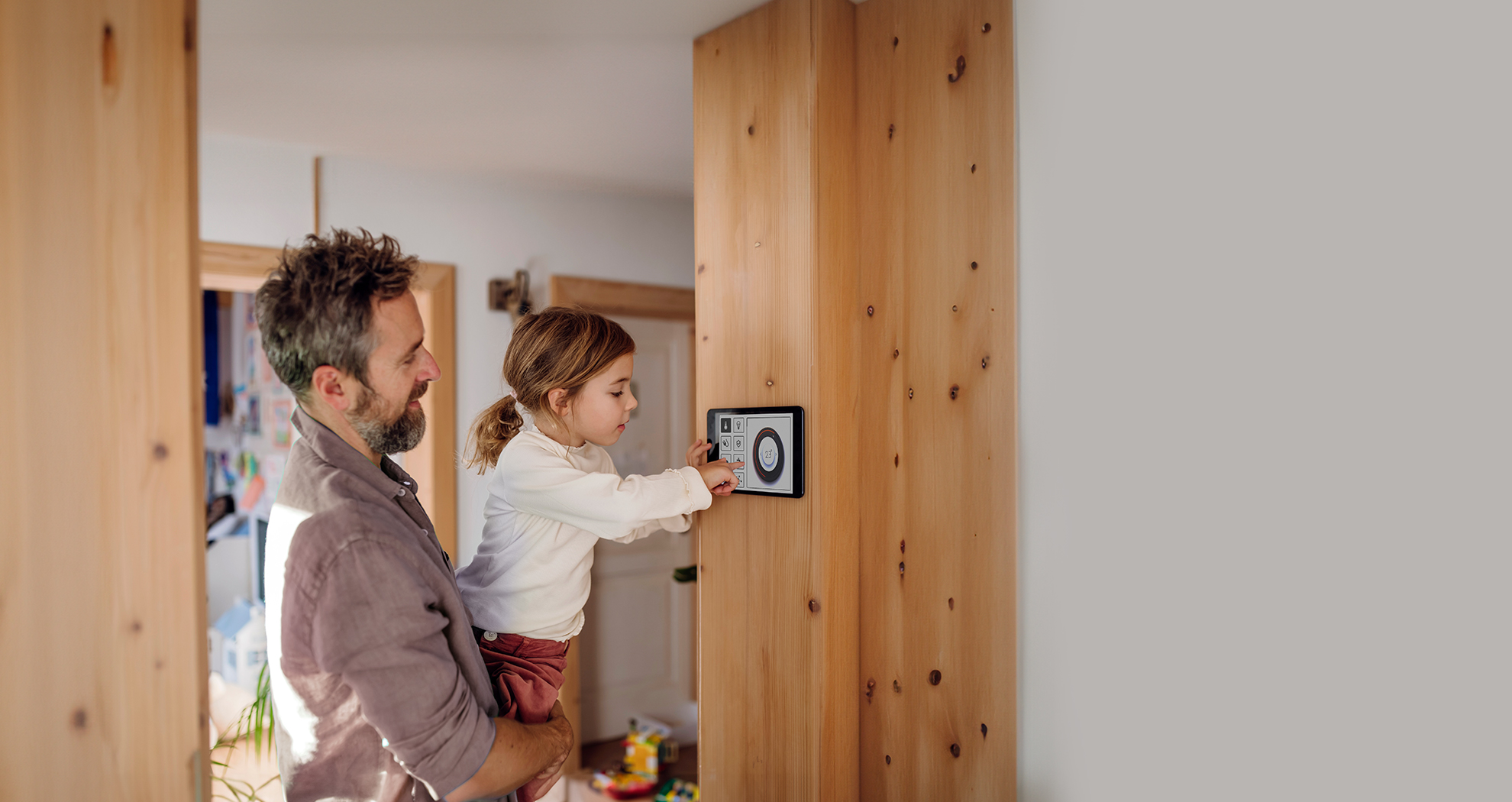 Father and daughter adjusting a smart home thermostat, illustrating energy-efficient upgrades financed by AIB’s home Energy Upgrade loan Scheme.