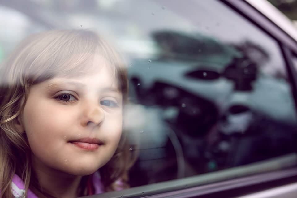 A close up of a young girl looking out a car window.