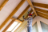 A man wearing a mask installing insulation above a window in the attic.
