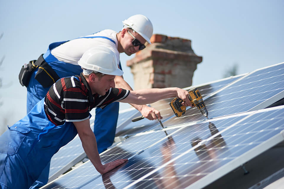 Workers installing solar panels on a roof.
