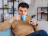 Man sitting on a sofa drinking from a mug looking at his phone.