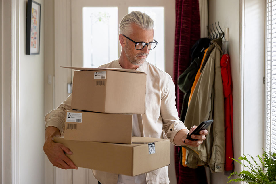 Man carrying boxes while looking at his phone.