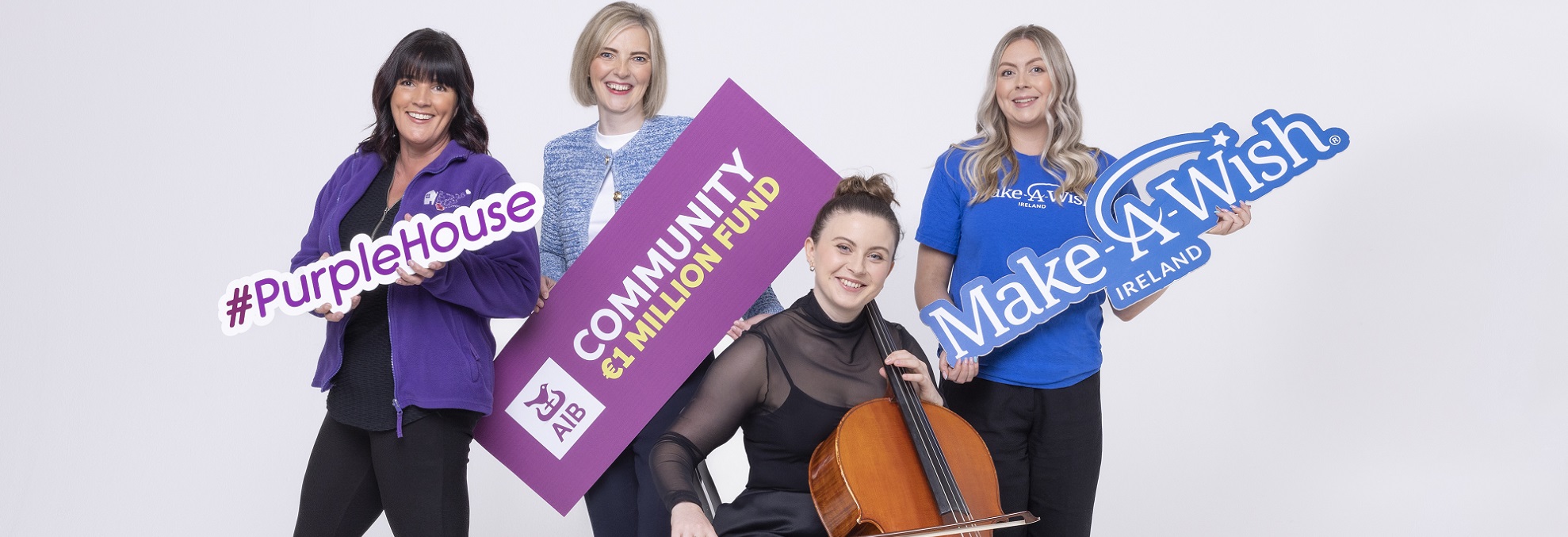  A group of women posing with Irish charity banners, such as make a wish and purple house.