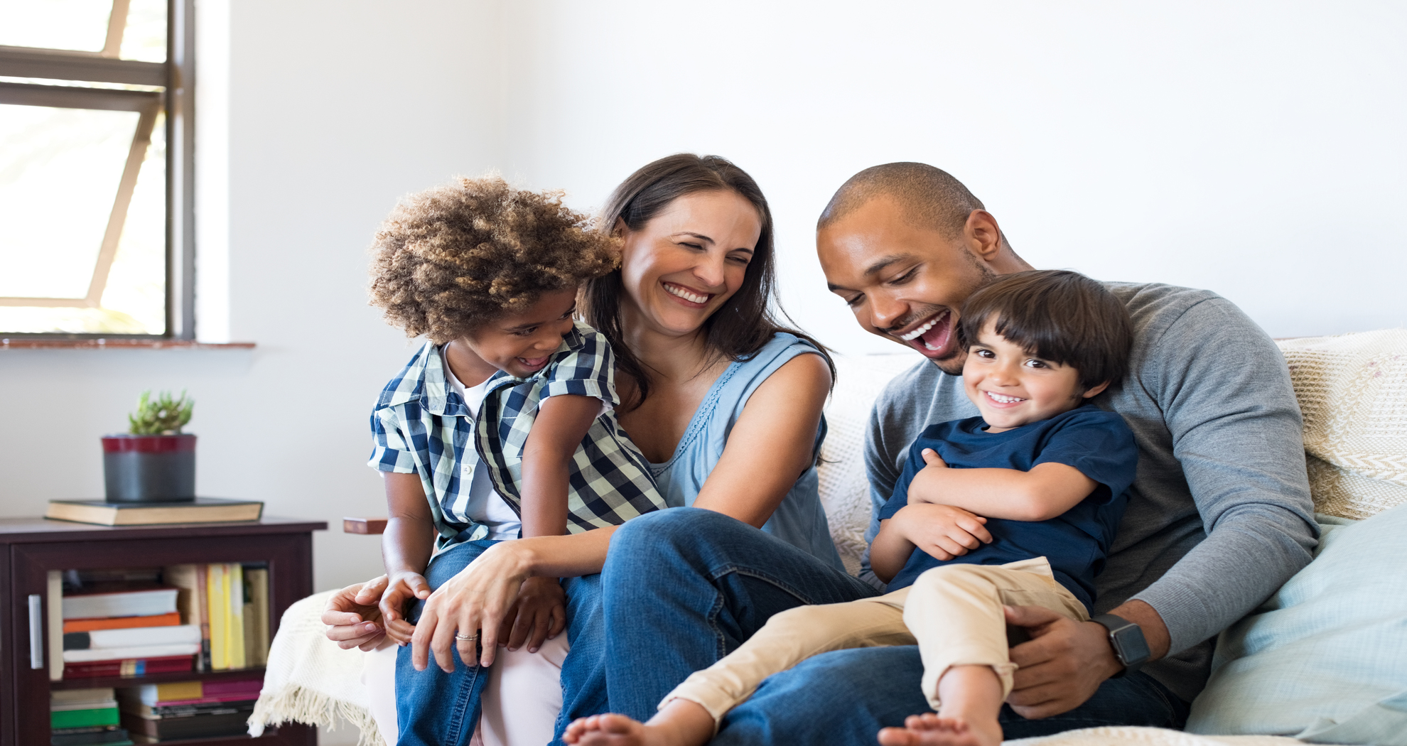 A happy family of four at home on the couch.